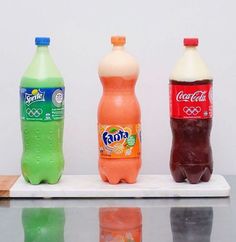 three bottles of soda sitting on top of a counter