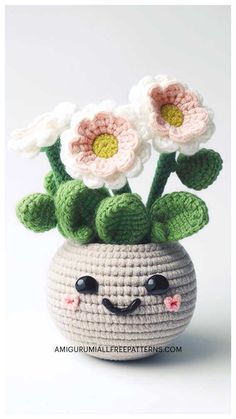 a crocheted flower pot with two flowers in it's face and eyes