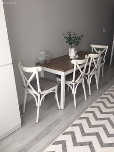 a dining room table with four chairs and a rug on the floor in front of it