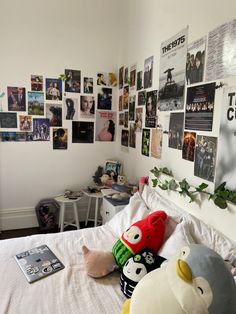 a bed with many pictures on the wall and stuffed animals sitting on top of it