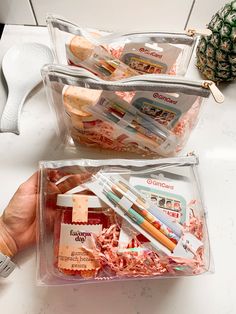 two clear bags filled with different items sitting on top of a white counter next to a pineapple