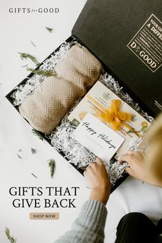 a woman is opening a gift box with the words gifts that give back written on it