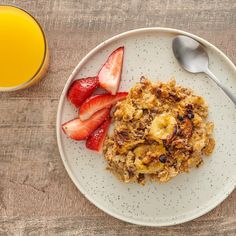 a white plate topped with oatmeal and fruit next to a glass of orange juice