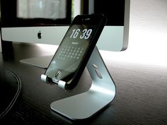 an iphone is sitting on top of a stand in front of a computer monitor and keyboard