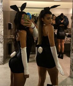 two women dressed up in bunny ears taking pictures with their cell phones while standing next to each other