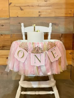 a pink and gold 1st birthday party with a one sign on the front of a chair