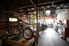 a motorcycle parked inside of a store next to a wooden table and shelves filled with bottles