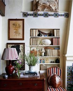 a living room filled with furniture and bookshelves next to a lamp on top of a dresser