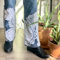 a pair of jeans with lace on them next to potted plants