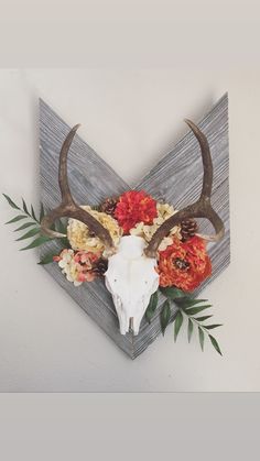 an animal skull with flowers on it mounted to the wall above a wooden paneled triangle