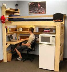 a man sitting at a desk in front of a computer on top of a wooden shelf