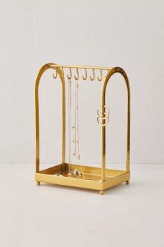 a gold jewelry holder with two necklaces hanging from it's sides on a white surface