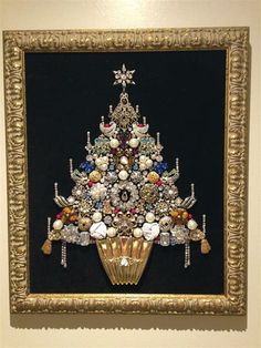 a christmas tree made out of buttons in a gold frame on a black wall with white trim