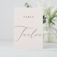 a card with the word table twelve written on it next to a vase filled with flowers