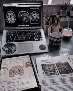 an open laptop computer sitting on top of a desk next to papers and other items