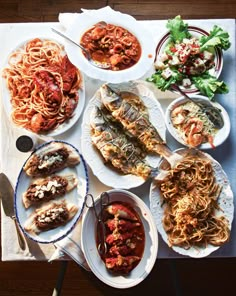 a table topped with plates of food and bowls of sauces on top of it