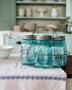 four mason jars sitting on top of a kitchen counter next to a white table cloth