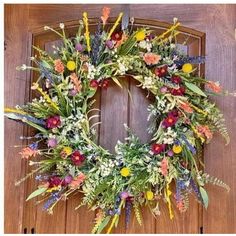 a wreath is hanging on the door with flowers and leaves around it, as well as other decorations