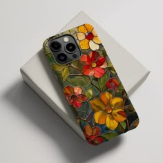 an iphone case with flowers on it sitting on top of a white surface next to a box