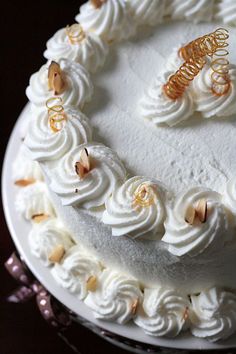 a cake with white frosting and gold decorations on it's edges, sitting on a glass platter