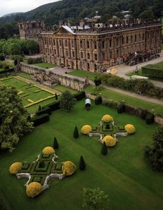 an aerial view of a large building in the middle of a lush green field with trees and bushes