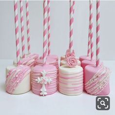 several pink and white cakes with candles in them