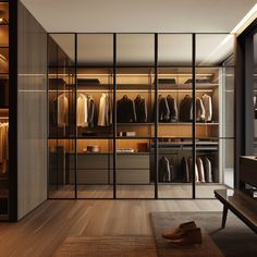 a walk in closet filled with lots of clothes and shoes next to a wooden bench