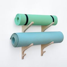 two yoga mats are hanging on the wall next to each other, one blue and one green