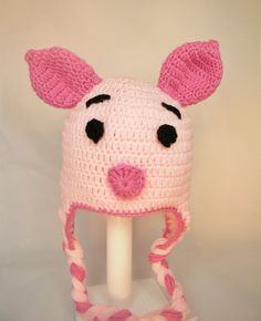 a crocheted pink and white hat with ears is on top of a stand