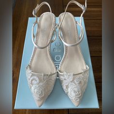 a pair of white wedding shoes sitting on top of a blue box with lace detailing