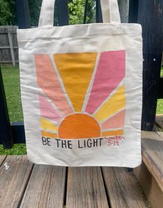 a tote bag sitting on top of a wooden bench in front of a fence