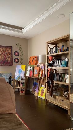 a living room filled with lots of furniture and art on the walls, along with bookshelves