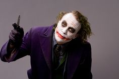 a man dressed as the joker holding a knife and pointing at something in his hand