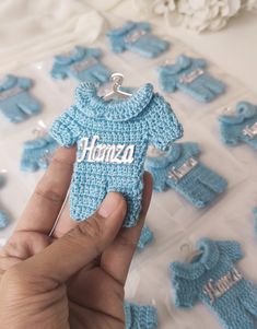 a hand holding a tiny blue crocheted baby's sweater ornament