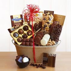 a gift basket filled with chocolates, cookies and candies on a wooden table