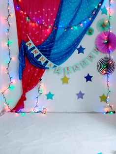 a birthday backdrop with stars and streamers on the wall, lights in the background