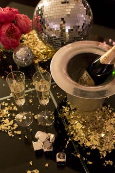 champagne being poured into a glass in front of disco balls and glasses on a table