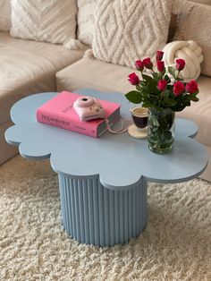 a table with flowers and a book on it in the middle of a living room