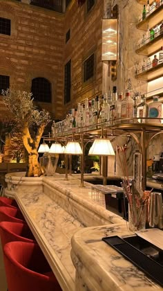 a bar with red chairs and bottles on the shelves in an old brick walled building