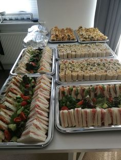 several trays filled with different types of food on top of a white table next to a window