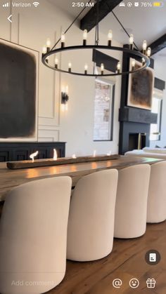 a dining room table with white chairs next to a fireplace and television on the wall