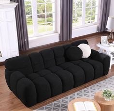 a large black couch sitting in a living room on top of a hard wood floor