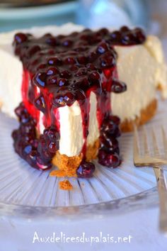 a piece of cheesecake with blueberries on top is sitting on a glass plate