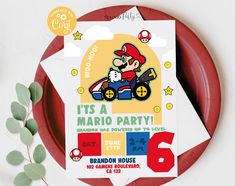 a mario birthday party is on the table next to a red plate and green leaves