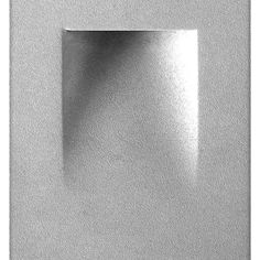 a square shaped metal object on a white surface with light reflecting off the wall behind it