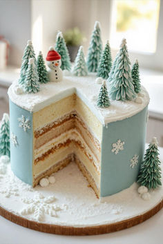 a frosted cake with trees and snow on the top is cut in half to show it's layers