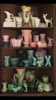 a shelf filled with lots of different colored vases and bowls on top of wooden shelves