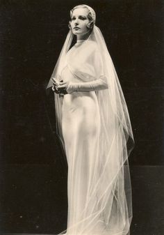 an old black and white photo of a woman in a wedding dress with a veil