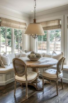 a dining room table with chairs and a bench in front of the window, next to a bay window