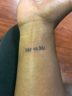 a person with a tattoo on their wrist saying me vs me and the word's in blue ink